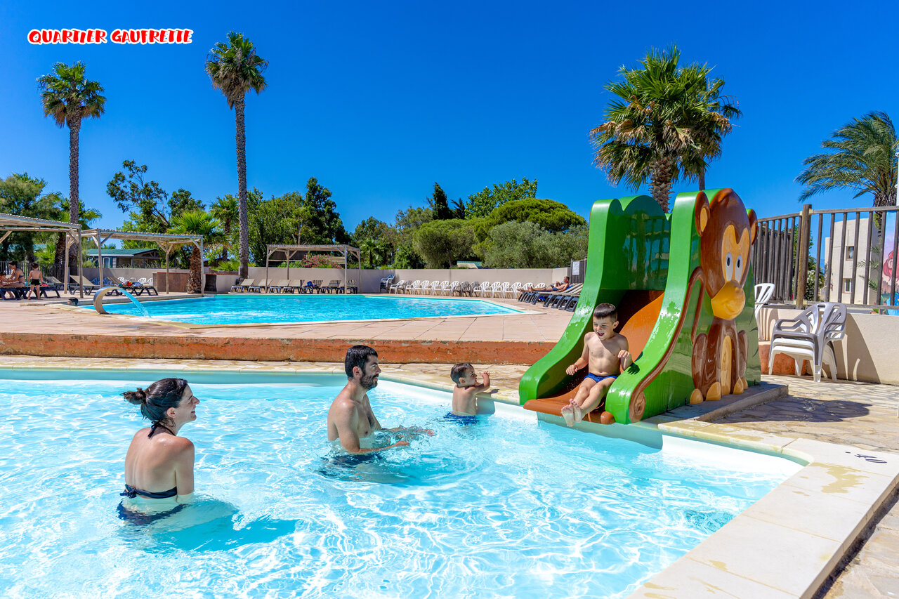 Piscine familiale avec toboggan enfant et palmiers au camping CAPFUN Las Bousigues � Le Barcar�s (66).