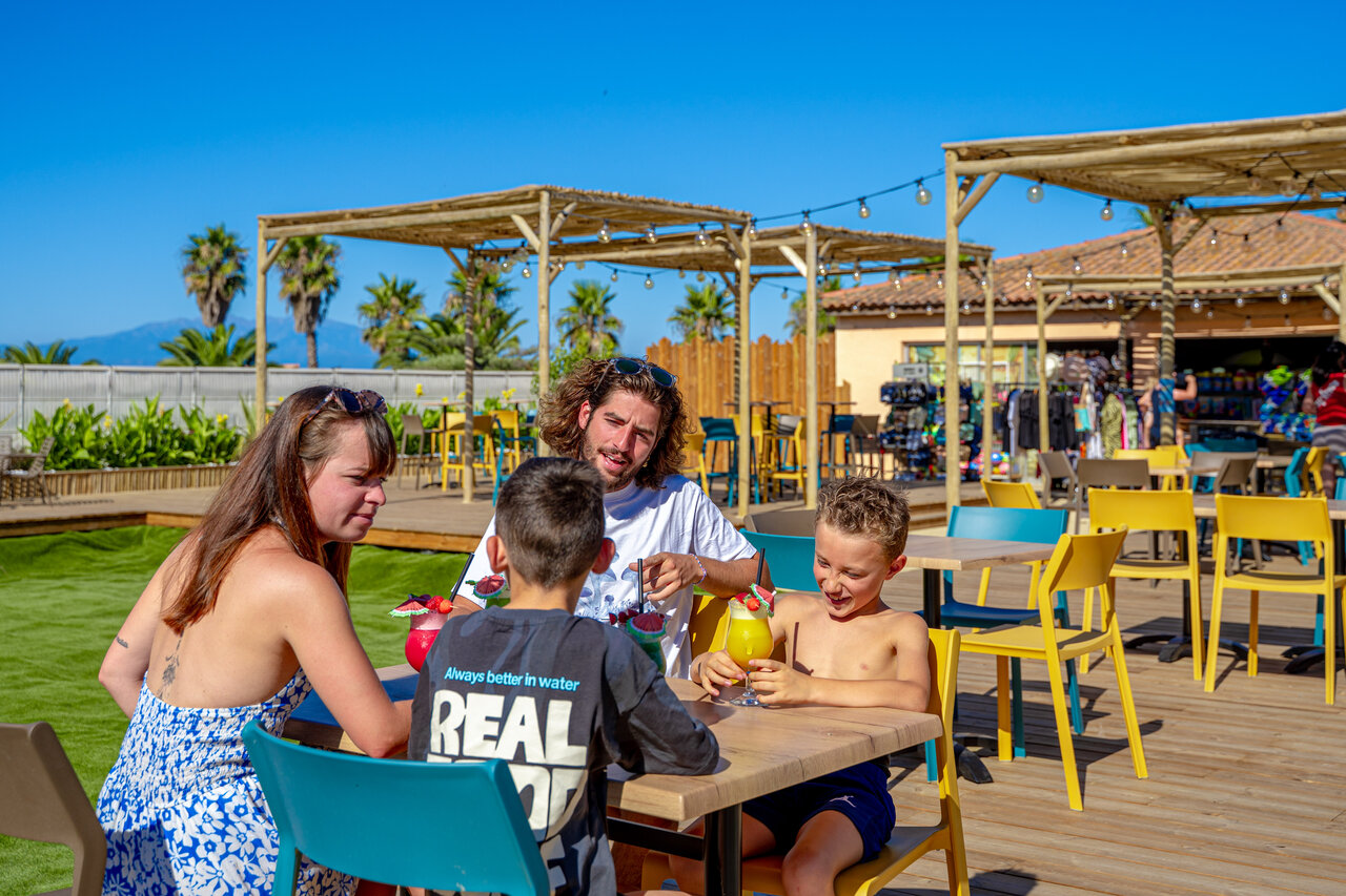 Famille souriante d�gustant des boissons sur la terrasse du bar au camping CAPFUN Las Bousigues � Le Barcar�s (66).