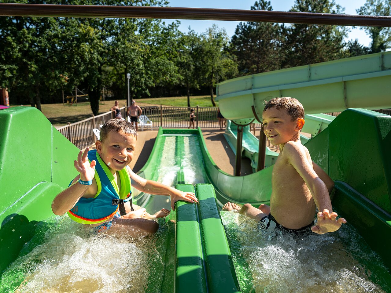 Enfants sur toboggan aquatique vert au camping CLICOCHIC Les Secrets de Padirac (46).