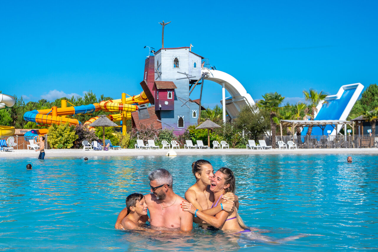 Famille souriante dans piscine avec toboggans aquatiques g�ants au camping CAPFUN Lila � LINXE (40).