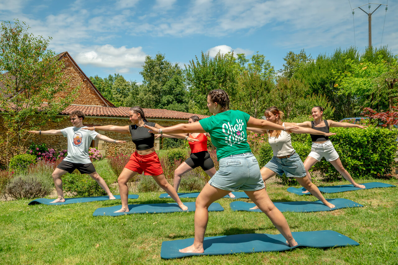 Groupe de personnes pratiquant le yoga en plein air au camping CLICOCHIC Linotte � Le Bugue (24).