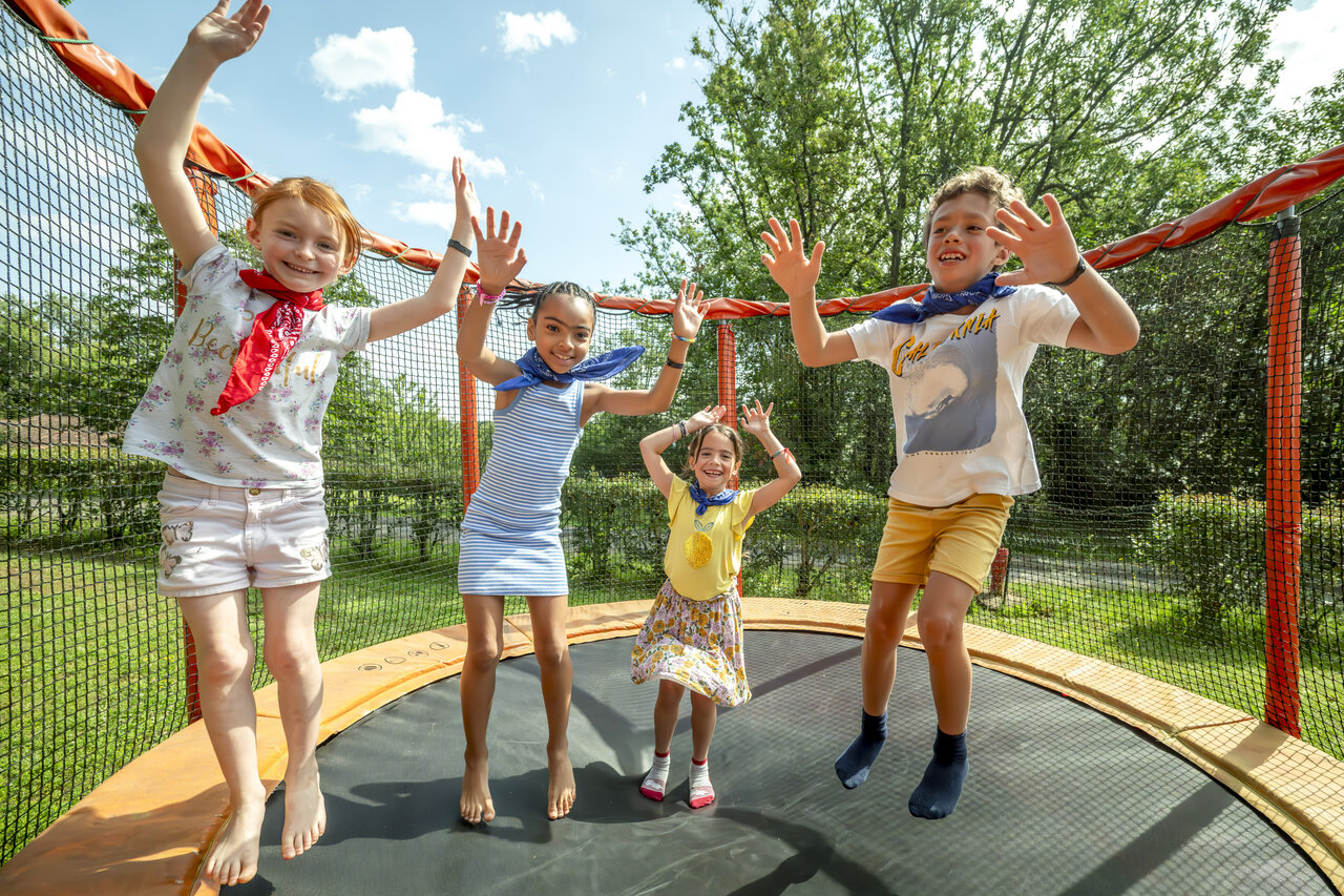 Enfants sautant sur trampoline ext�rieur au camping CLICOCHIC Linotte � Le Bugue (24).