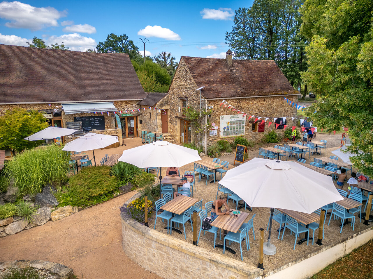 Terrasse ext�rieure du restaurant et bar avec parasols au camping CLICOCHIC Linotte, Le Bugue.