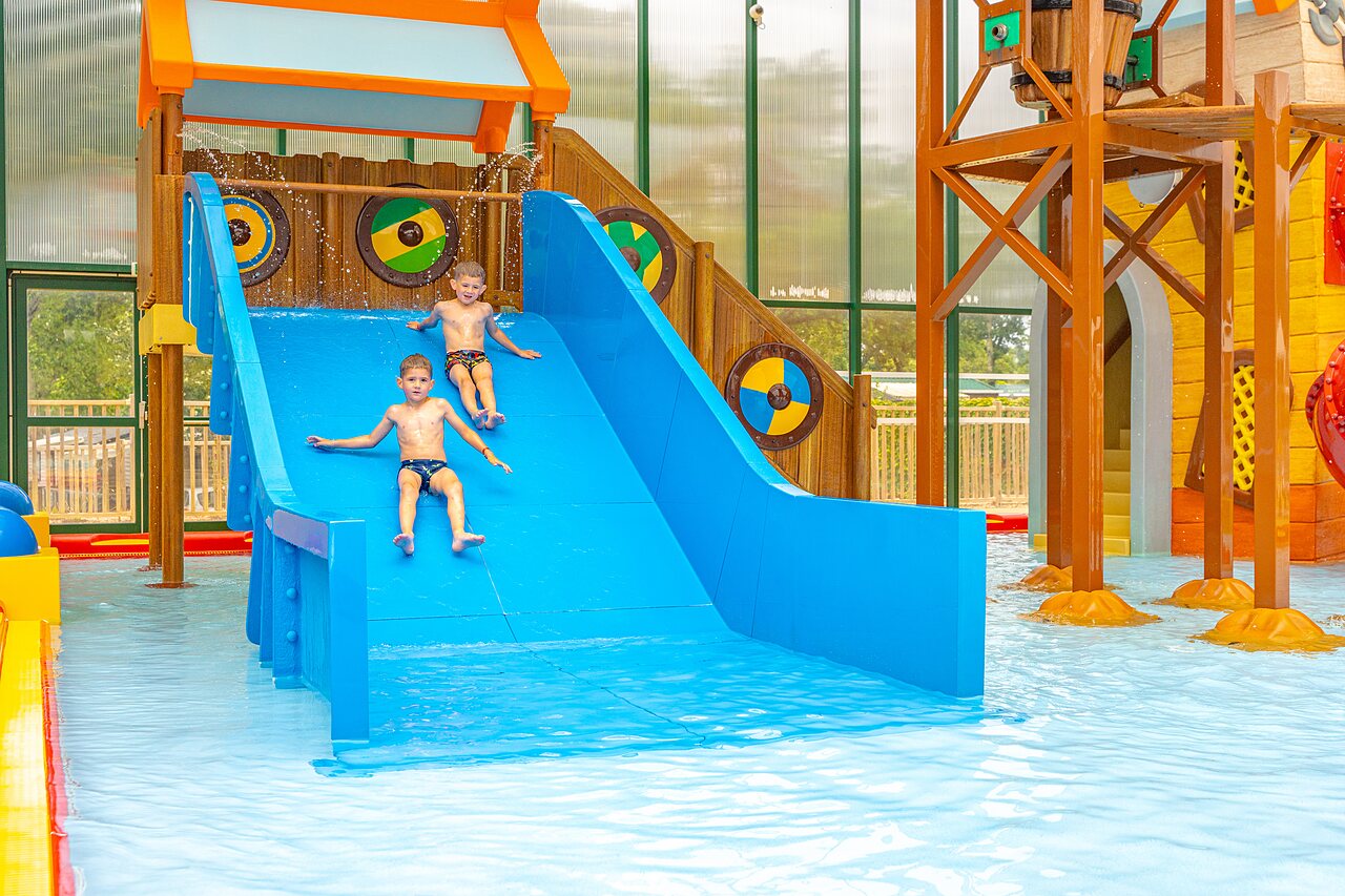 Deux enfants sur toboggan aquatique bleu dans piscine couverte au camping CAPFUN Lodge � SARZEAU (56).