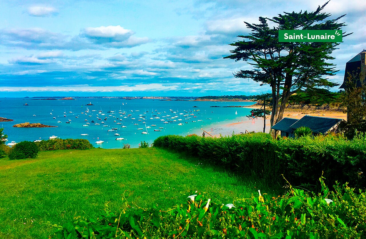 Plage et baie de Saint-Lunaire, Bretagne, avec nombreux bateaux au mouillage.