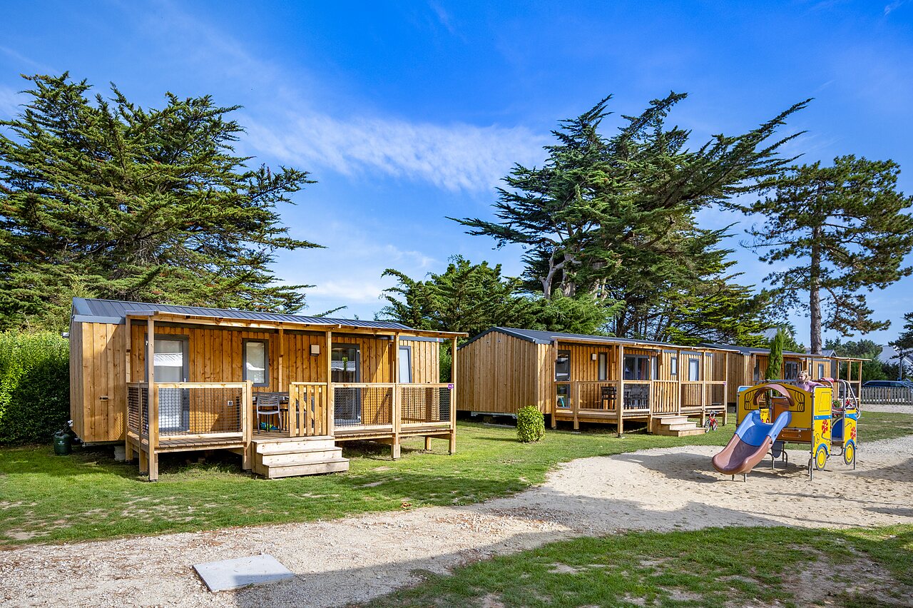 Mobil-homes en bois, terrasses et aire de jeux enfants au camping CLICOCHIC Longchamp.