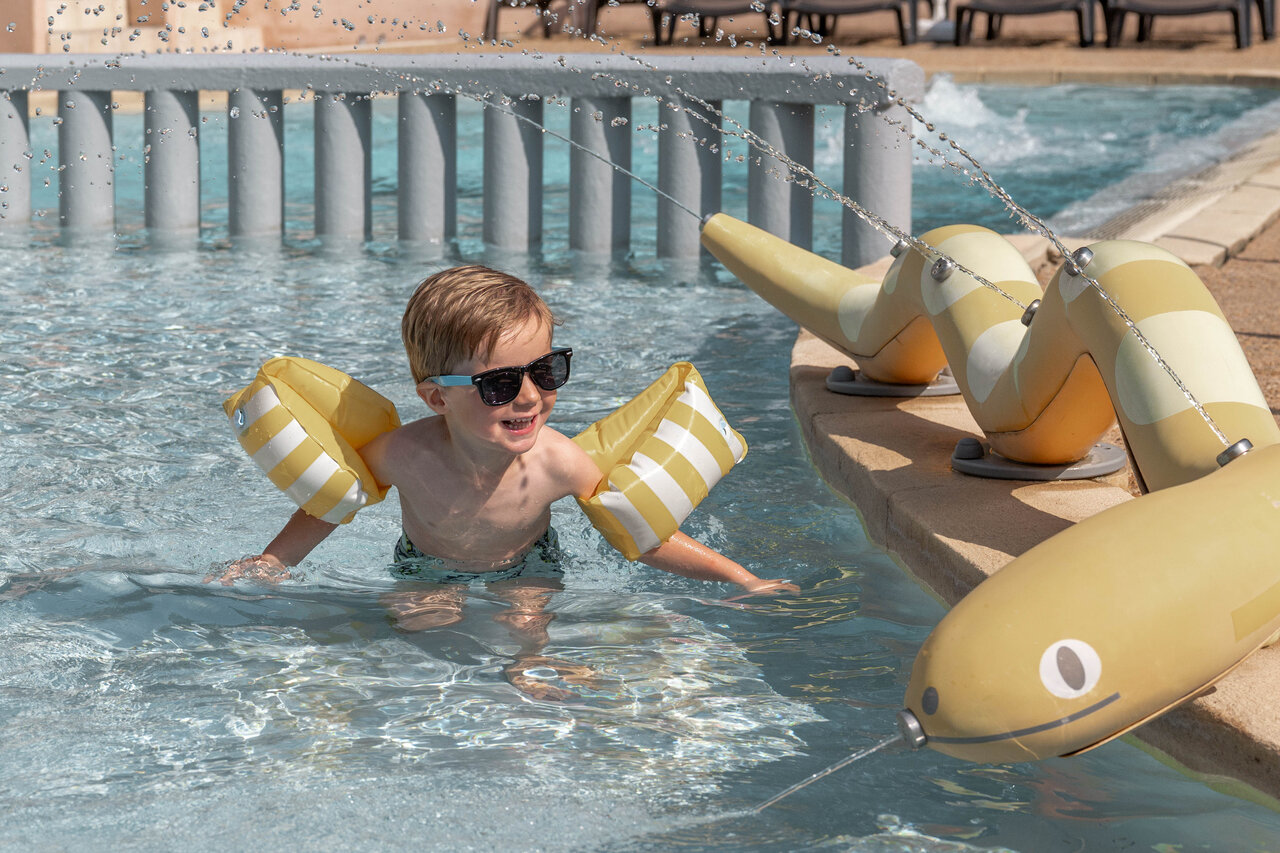 Enfant souriant, brassards, jeux d'eau piscine camping CLICOCHIC Lou Cantaire � Fayence.