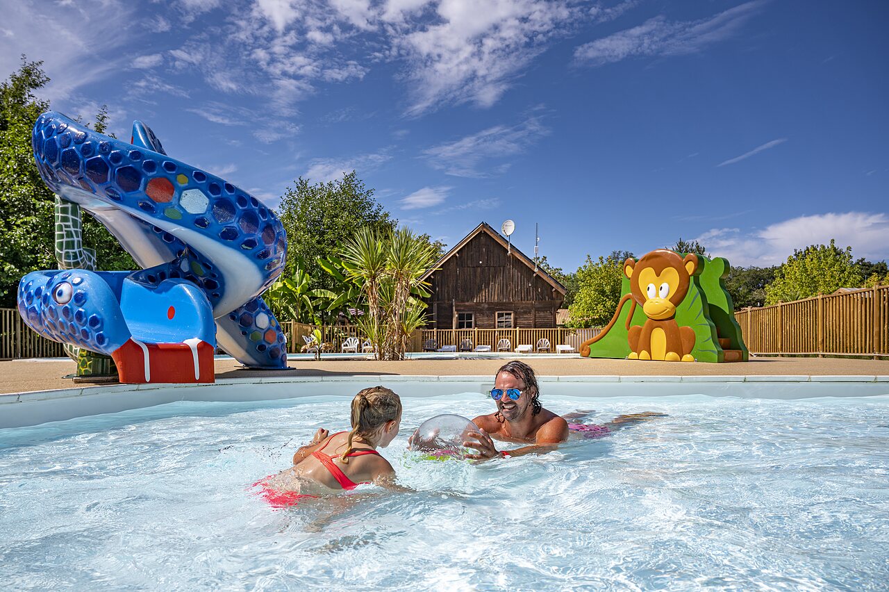Homme et enfant jouent dans la piscine avec toboggans au camping CAPFUN Lou Puntaou � LEON (40).
