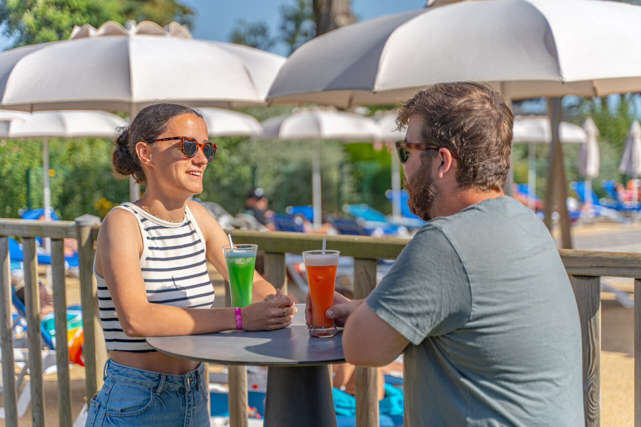 Couple souriant prenant un verre au bar de la piscine au camping CAPFUN Madrague � PORNIC (44).