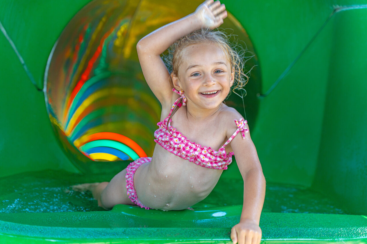 Enfant souriant descendant un toboggan aquatique color� au camping CAPFUN Madrague � PORNIC (44).