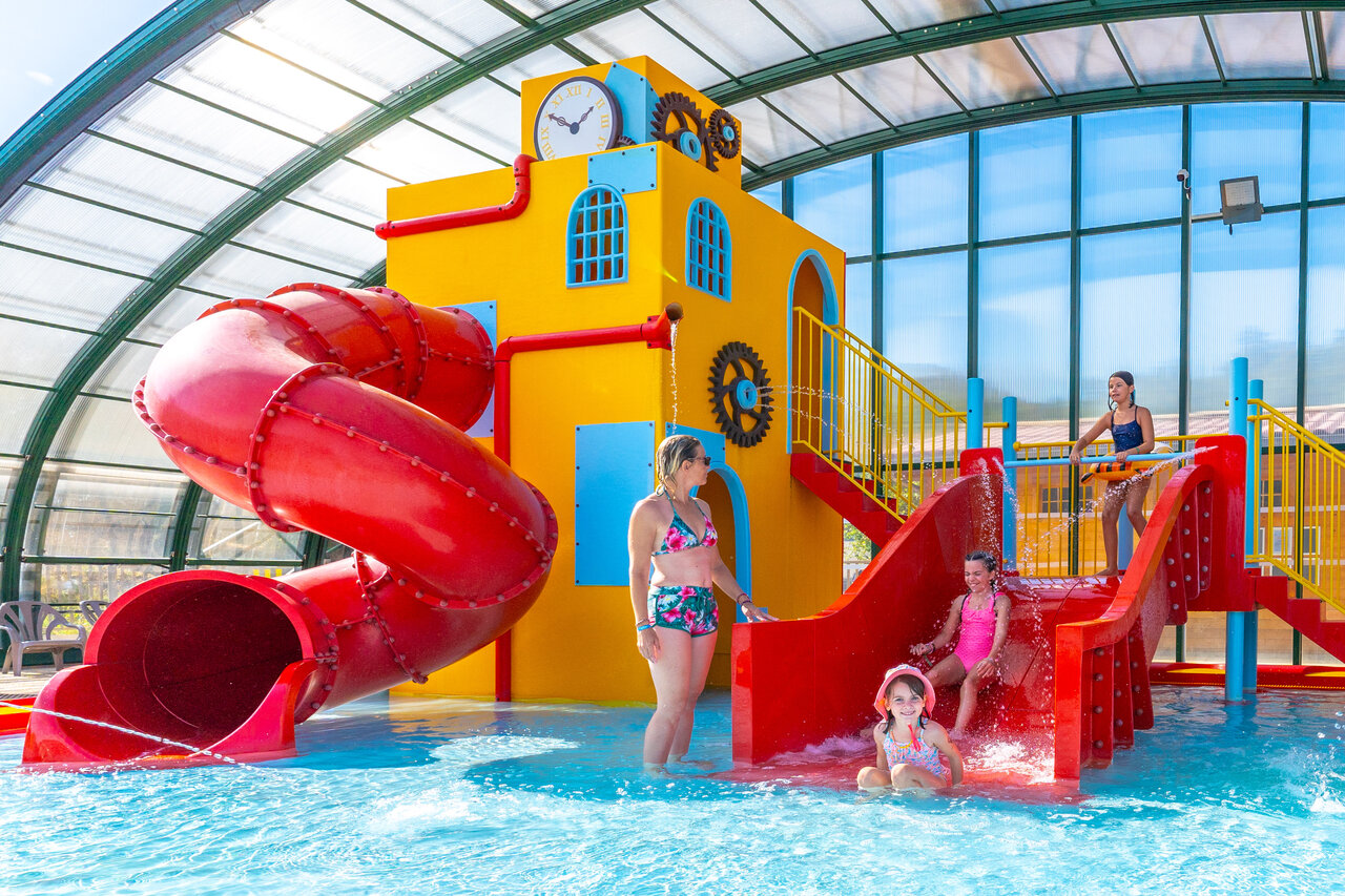 Piscine couverte avec toboggans et jeux d'eau au camping CAPFUN Merle Roux.