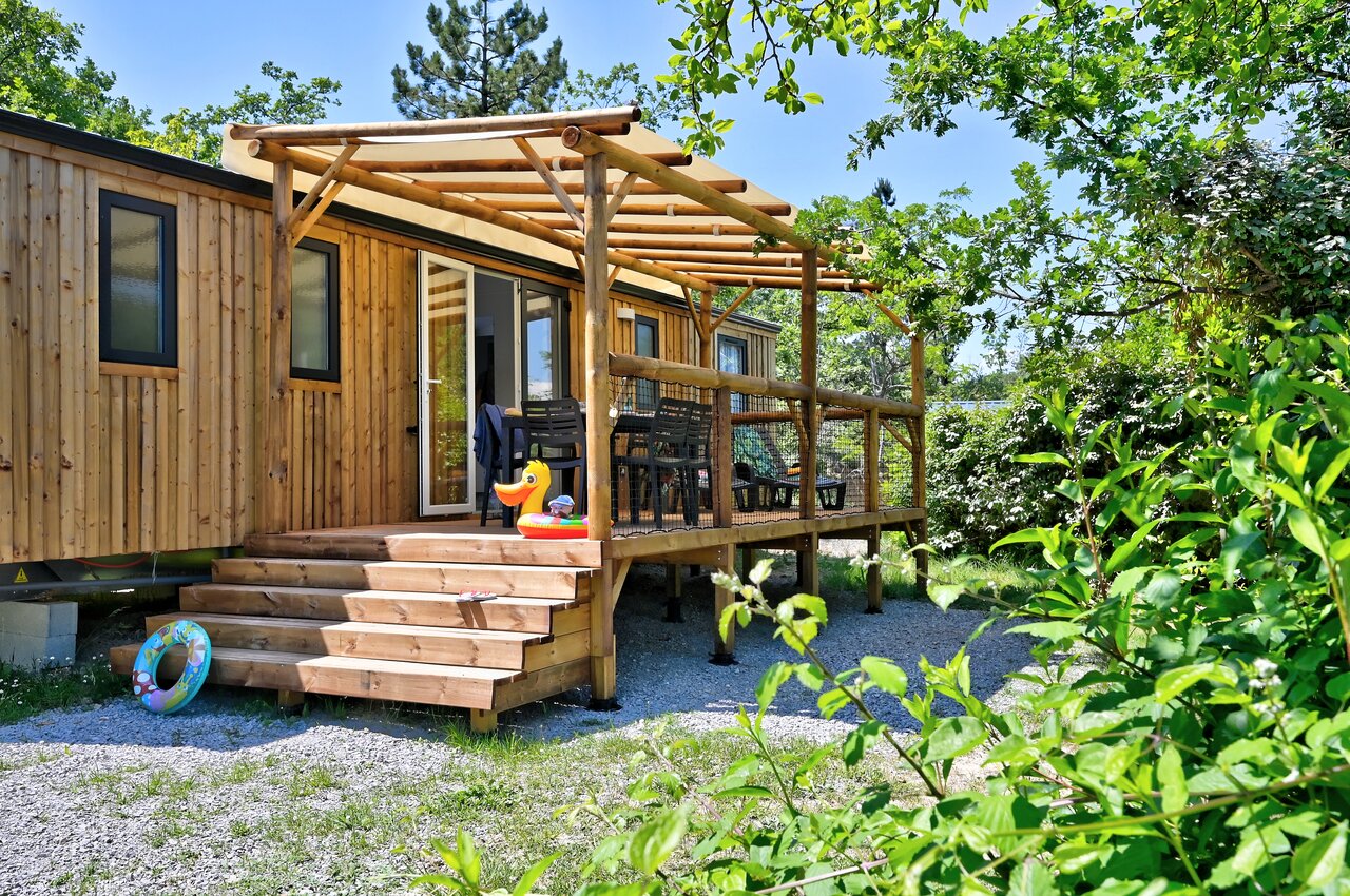 Mobil-home en bois avec terrasse ombrag�e, mobilier ext�rieur et verdure au camping CAPFUN Merle Roux � Baix (07).