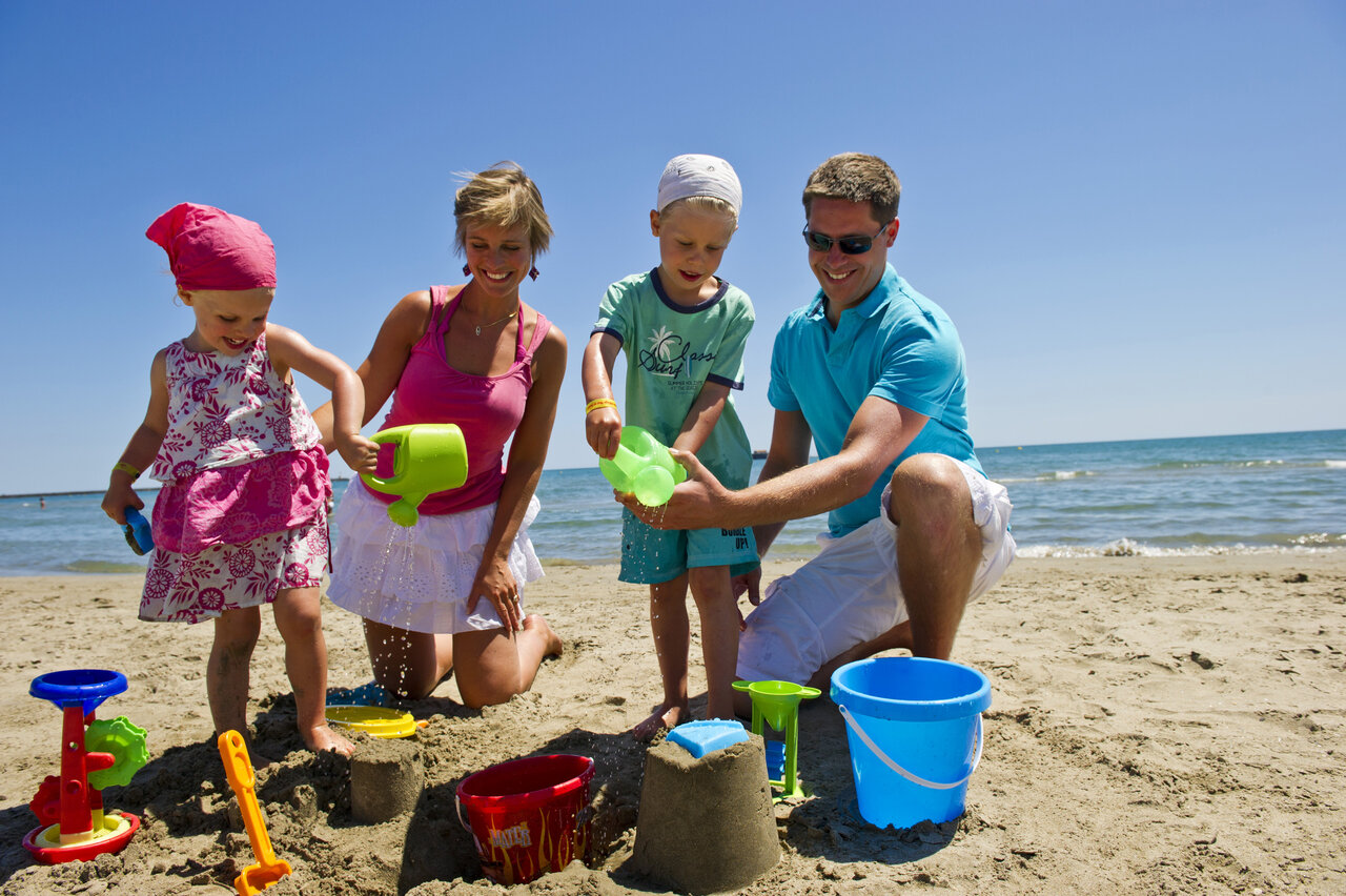 Famille construisant ch�teaux de sable sur la plage au camping CAPFUN Mer et Soleil � Cap d'Agde.