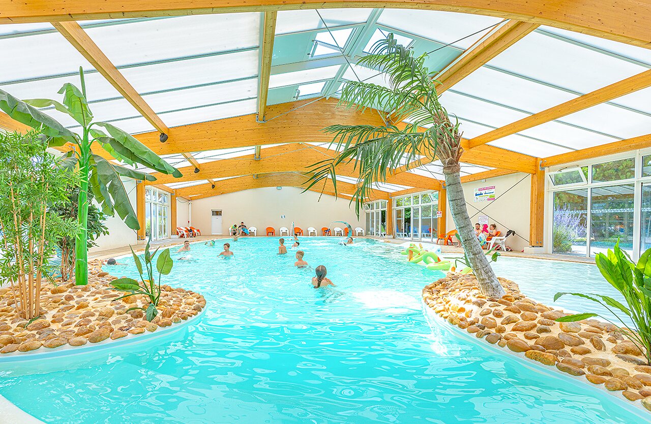 Piscine int�rieure chauff�e avec palmiers d�coratifs au camping VAGUES OCEANES Micheli�re � Givrand (85).