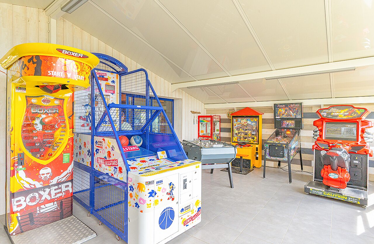 Salle de jeux avec bornes d'arcade, flippers et baby-foot au camping VAGUES OCEANES Micheli�re � Givrand (85).