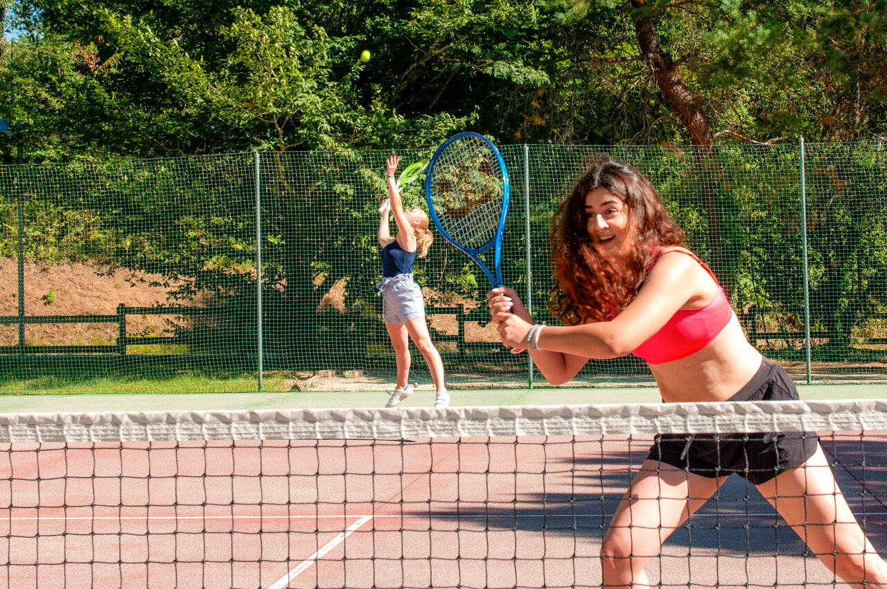 Jeunes femmes jouant au tennis sur court ensoleill� au camping CAPFUN Moulinal � BIRON (24).