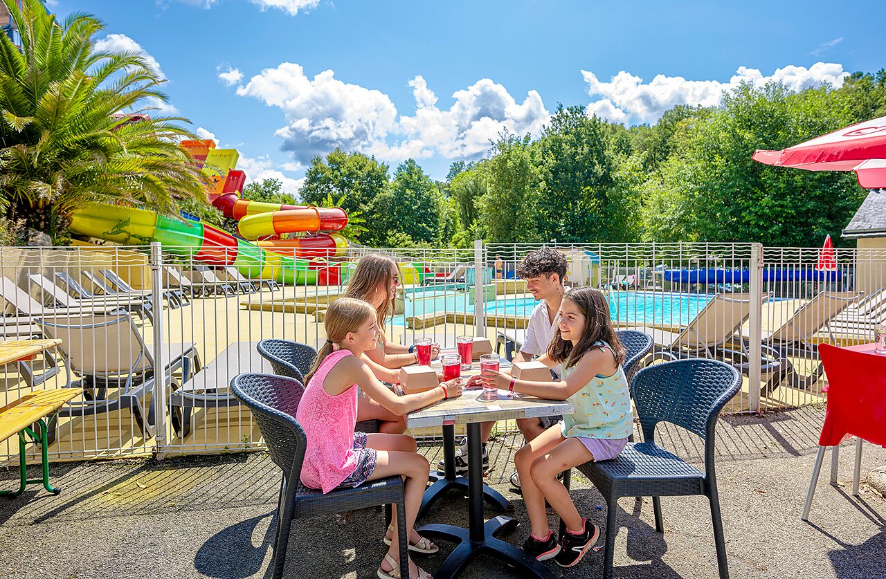 Famille profitant de boissons pr�s des toboggans aquatiques et piscine au camping VAGUES OCEANES Moulin de Cadillac � Noyal-Muzillac (56).