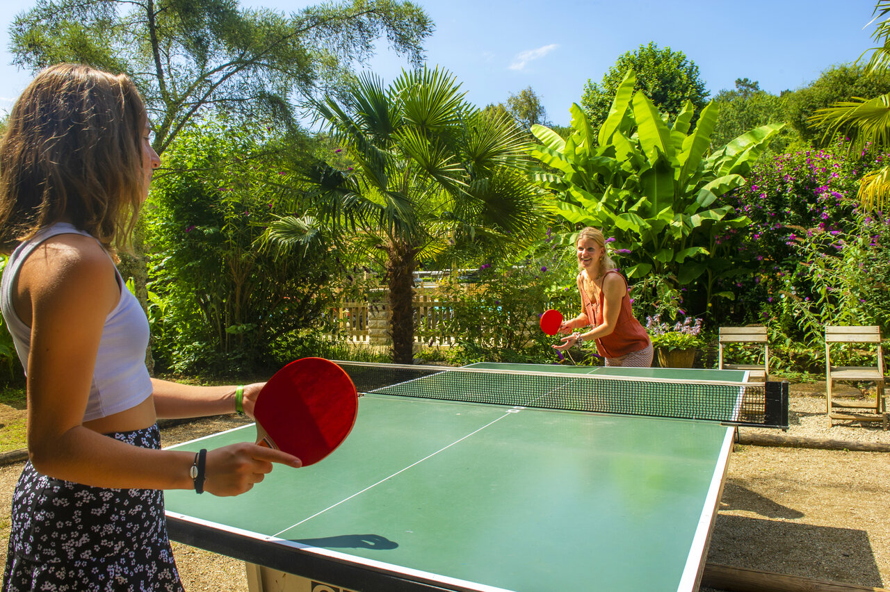 Deux femmes jouent au tennis de table en ext�rieur au camping CLICOCHIC Moulin du Roch.