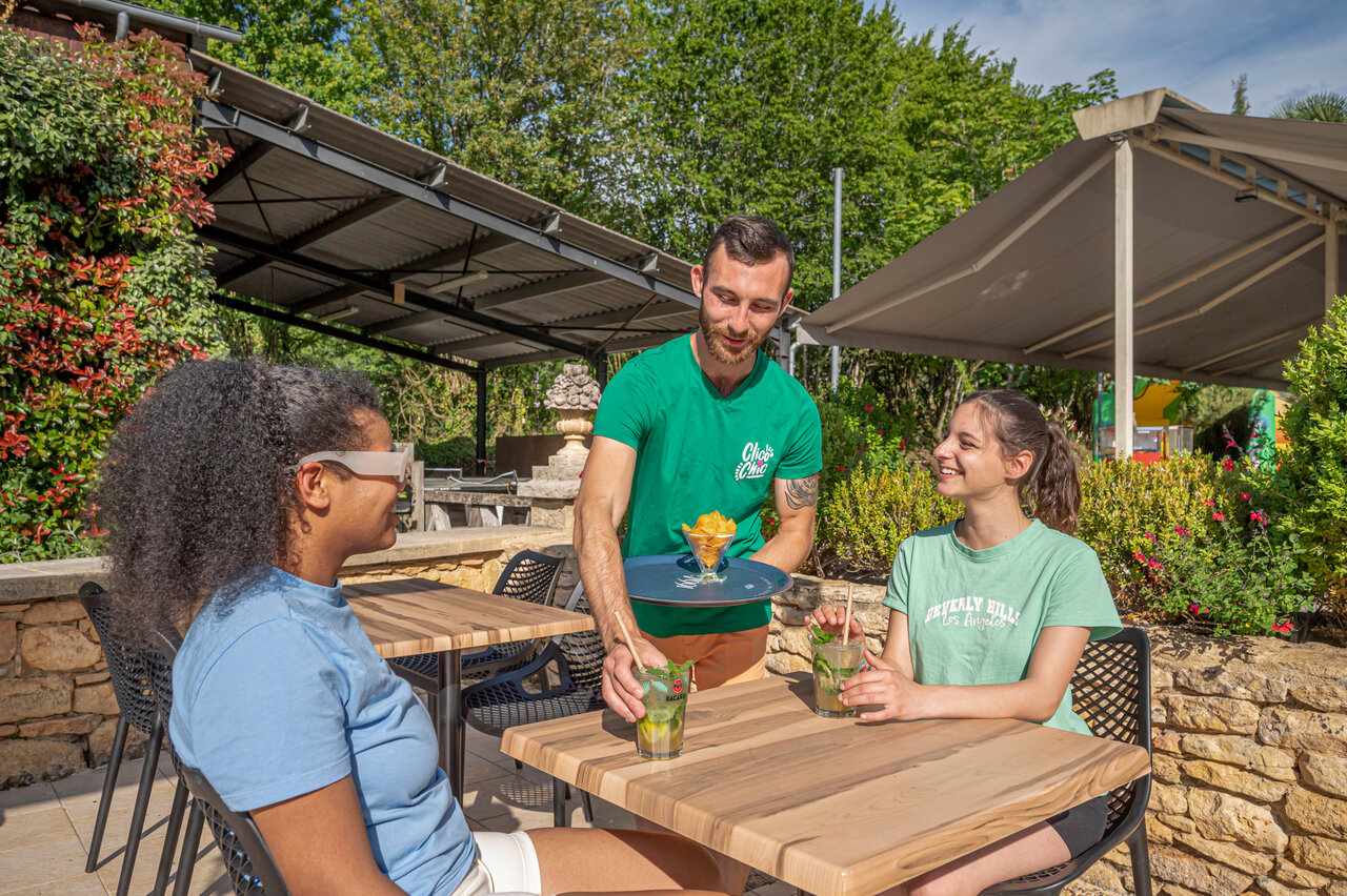 Serveur servant boissons sur la terrasse au camping CLICOCHIC Moulin du Roch � Saint Andre D'Allas (24).