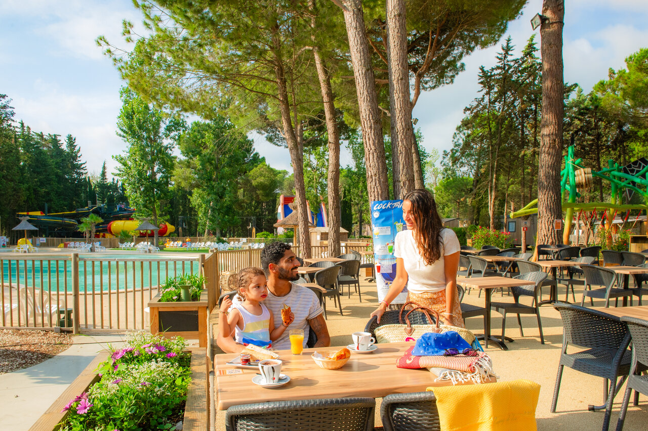 Famille d�jeunant en terrasse pr�s de la piscine au camping CAPFUN Or � La Grande Motte (34).