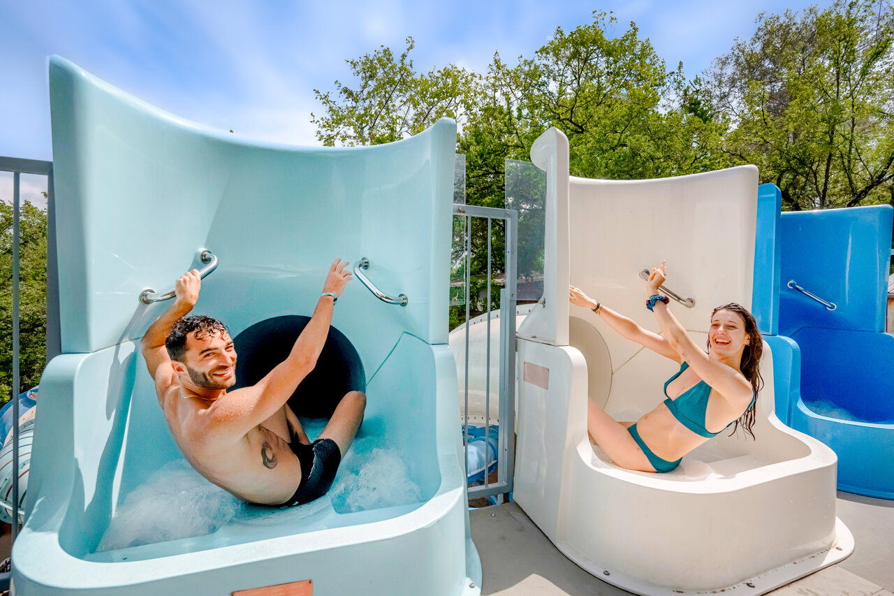 Couple souriant descendant des toboggans aquatiques au camping CLICOCHIC Or�e d'Azur � OPIO (06).