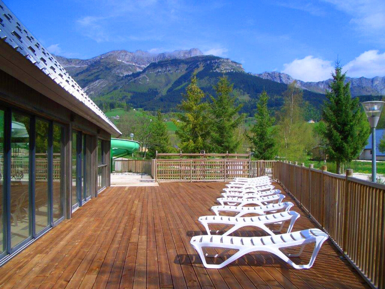 Terrasse en bois, transats, toboggan, montagnes au camping CAPFUN Oursi�re � Villard de Lans (38).