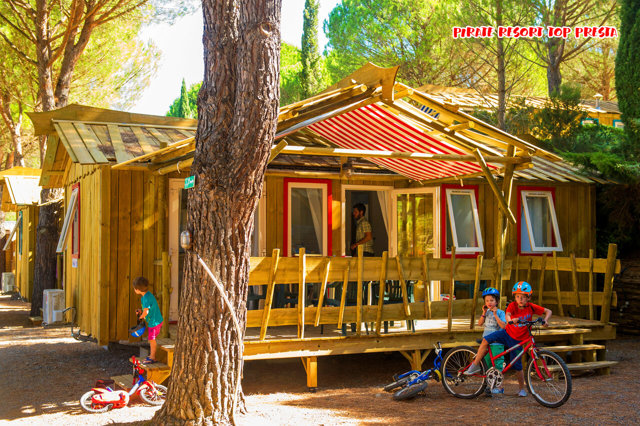 Mobil-home en bois, enfants jouant � v�lo au camping CAPFUN Pachacaid � La Mole (83).