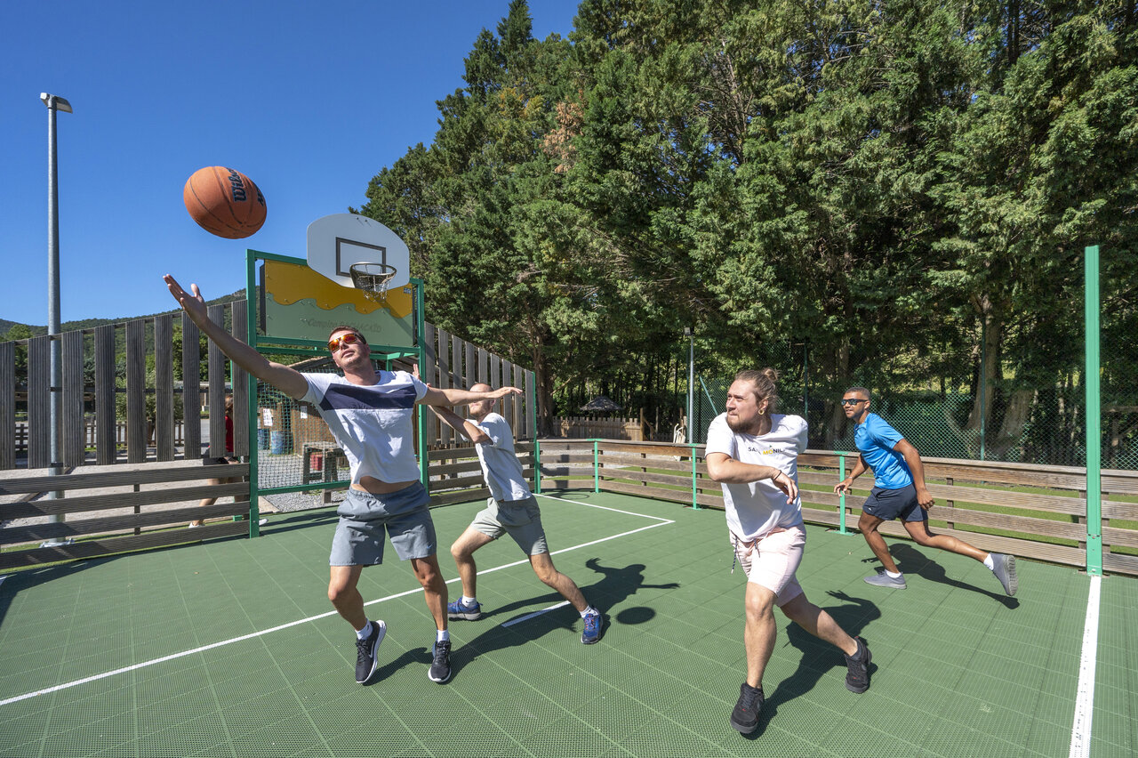 Adultes jouant au basketball sur terrain multisport au camping CAPFUN Pachacaid � La Mole (83).