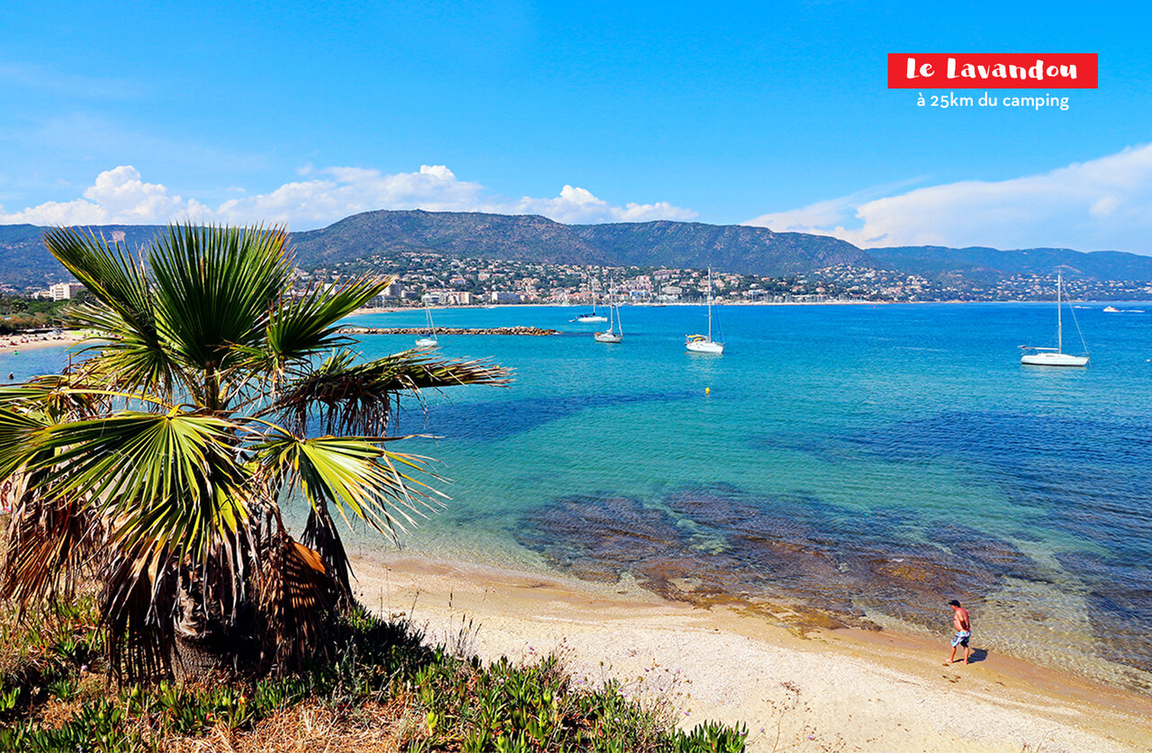 Plage de sable, mer turquoise et bateaux au Lavandou, destination touristique proche.