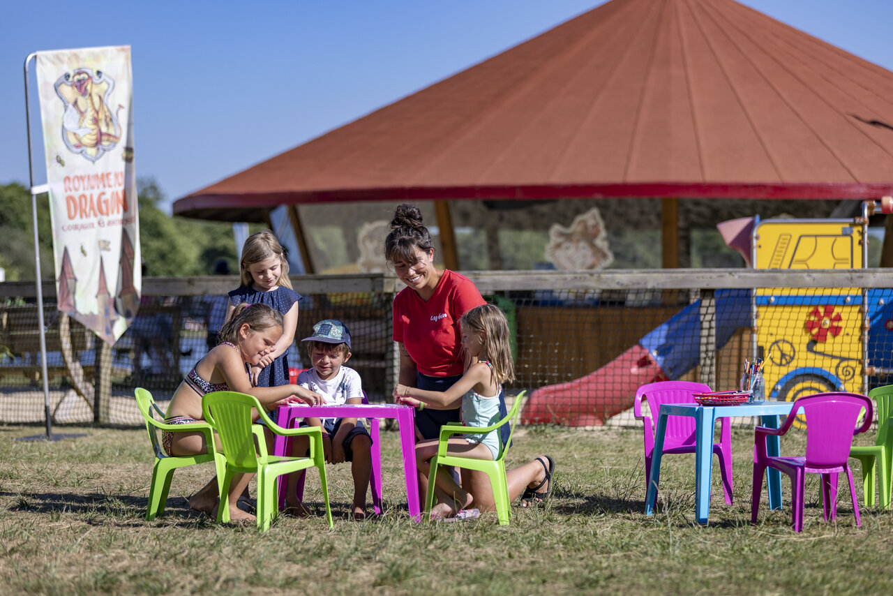 Animator en kinderen bezig met creatieve activiteit op camping CAPFUN Paillotte in AZUR (40).