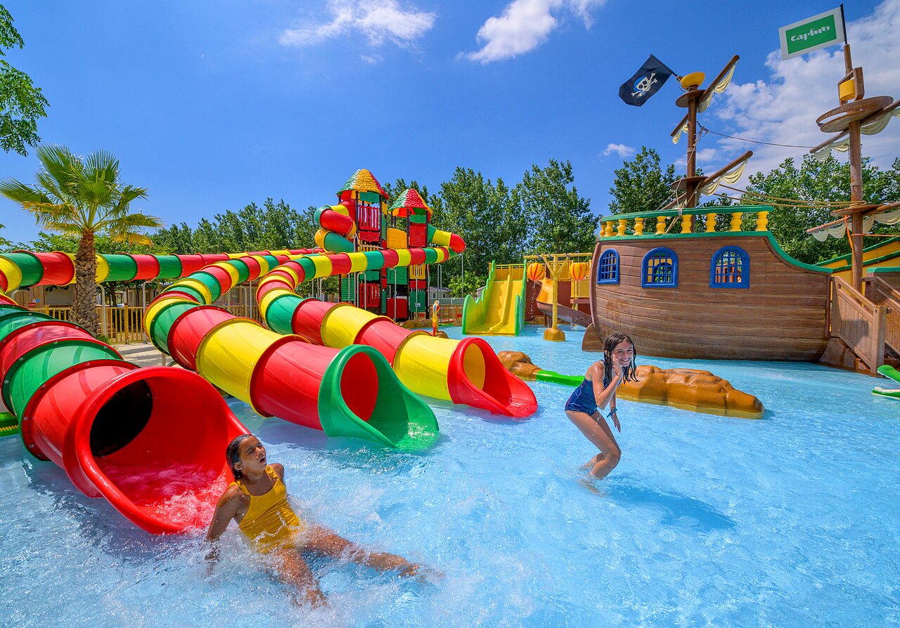 Toboggans aquatiques color�s, bateau pirate et enfants jouant au camping CLICOCHIC Palmira Beach.