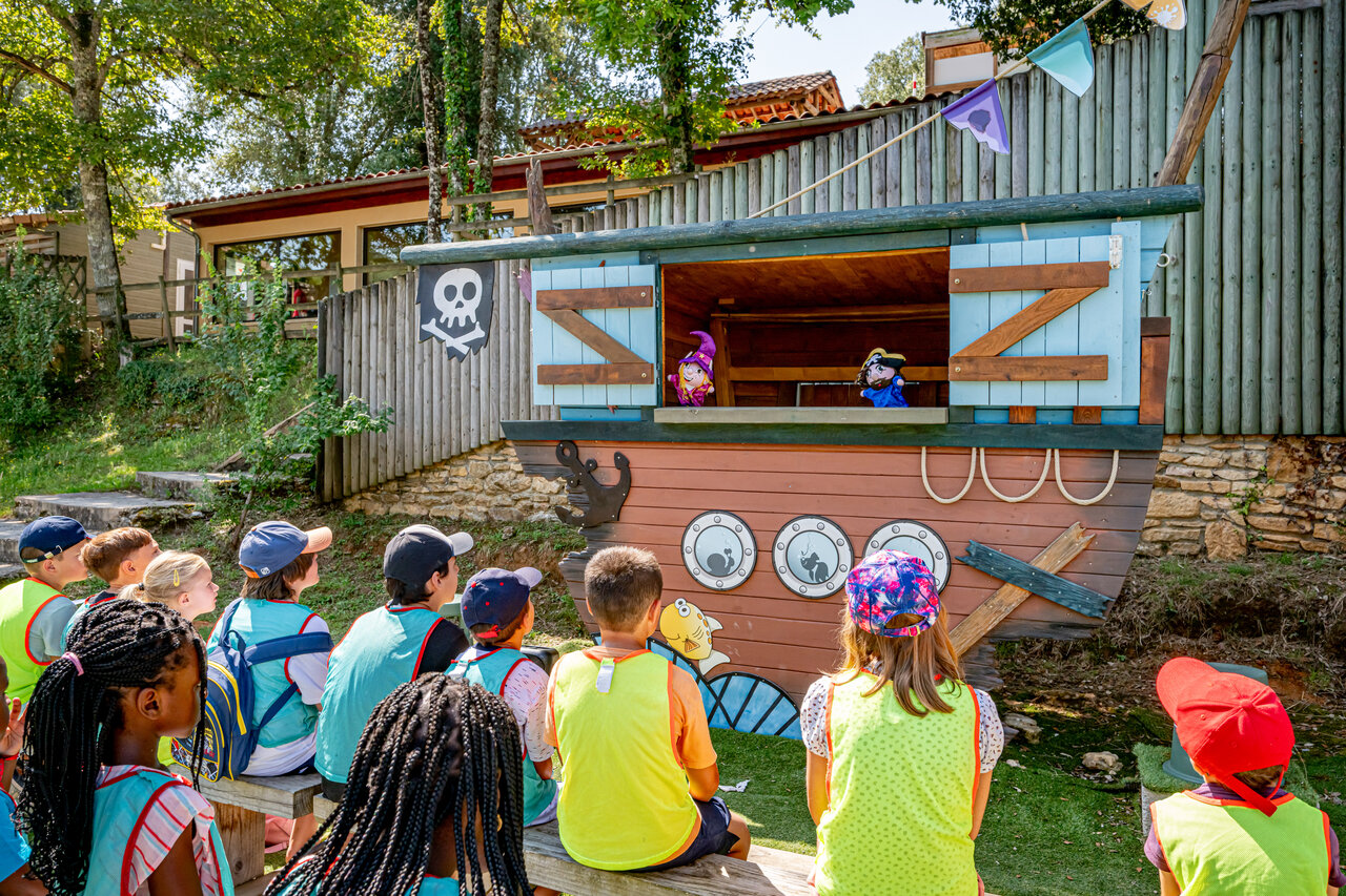 Enfants regardant un spectacle de marionnettes sur sc�ne pirate au camping CAPFUN Palombi�re � Sarlat (24).