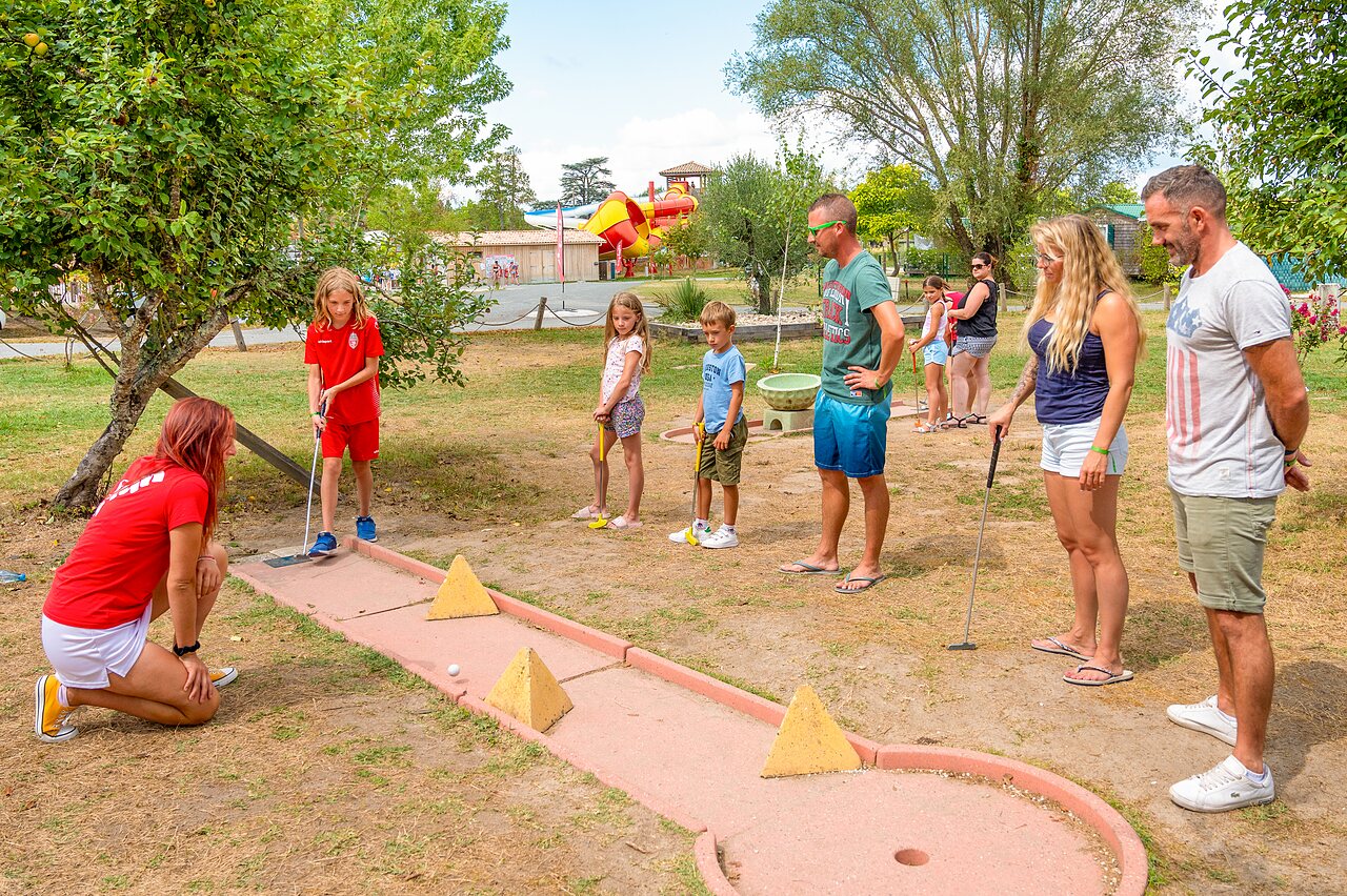 Famille et enfants jouent au mini-golf avec animateur au camping CAPFUN Paradis de Bazas � BAZAS (33).
