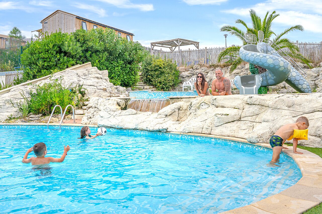 Famille profitant de la piscine avec toboggan et cascades au camping CLICOCHIC Petit Nice � PYLA SUR MER (33).