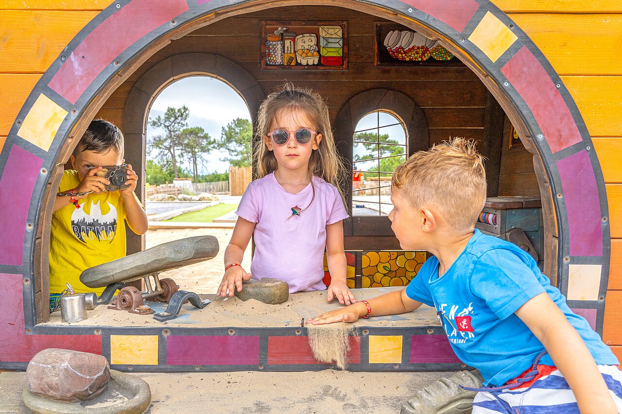 Enfants jouant dans une aire de jeux avec sable et cabane en bois au camping CLICOCHIC Petit Nice � PYLA SUR MER (33)