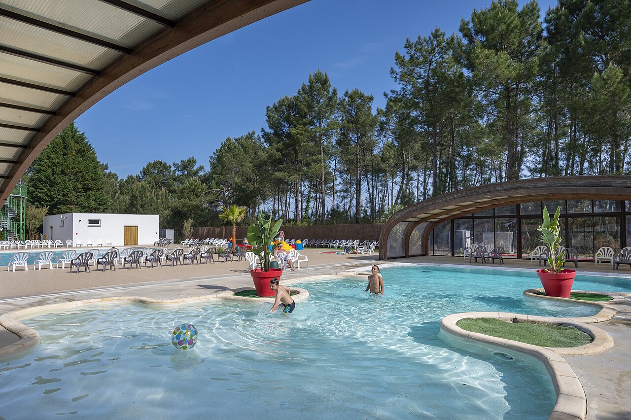 Piscine ext�rieure avec enfants jouant et zone couverte au camping CAPFUN Pin�da � CAZAUX (33).