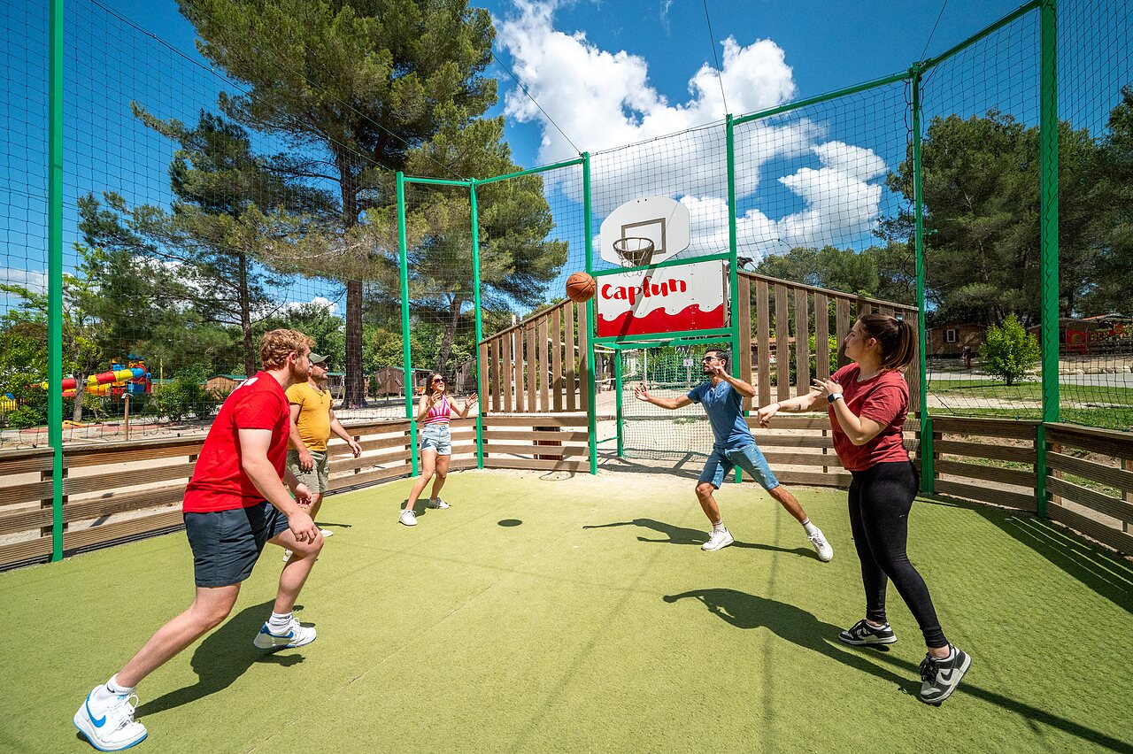 Terrain multisport, amis jouent basketball au camping CAPFUN Pin�des du Luberon (84).