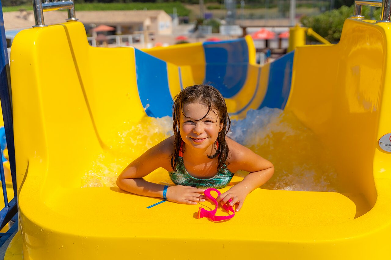 Enfant souriante sur toboggan jaune au camping CAPFUN La Pin�de de Grimaud (83).