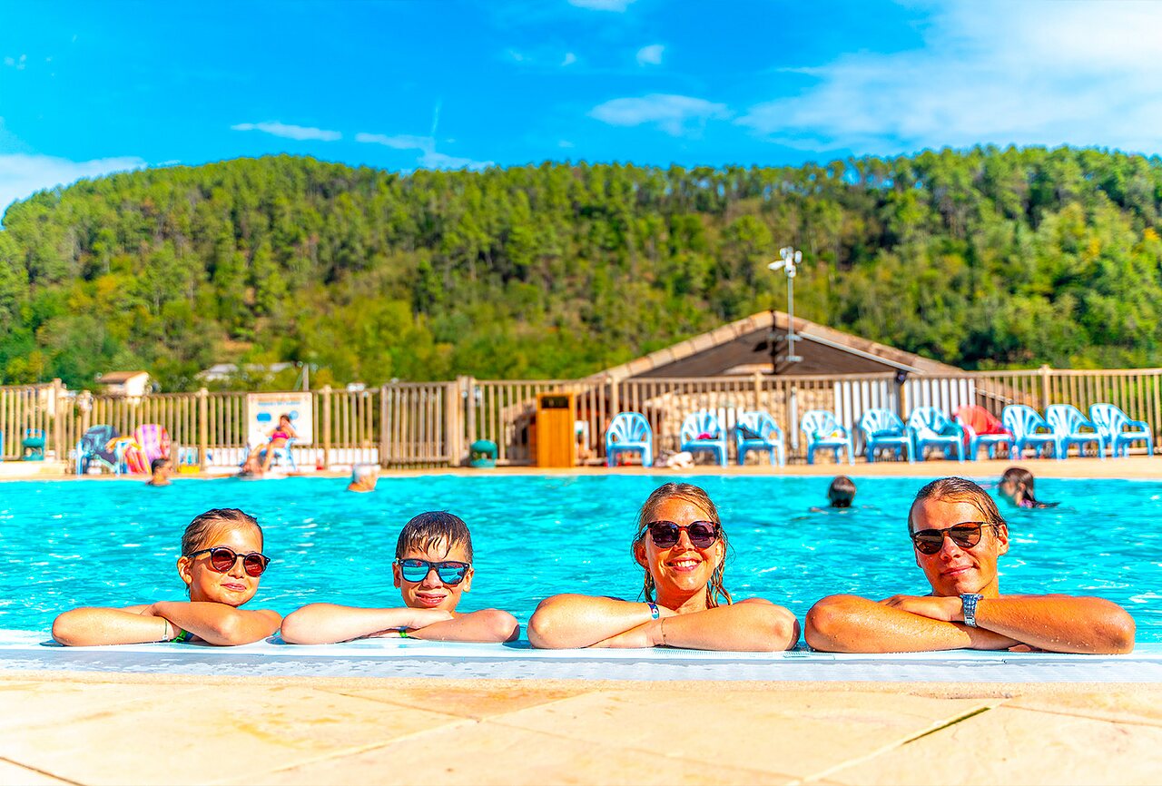 Enfants et adultes souriants dans la piscine au camping CAPFUN Plantas (07).