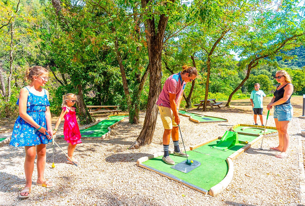 Famille jouant au mini-golf sur un parcours ombrag� au camping CAPFUN Plantas � SAINT VINCENT DE DURFORT (07).