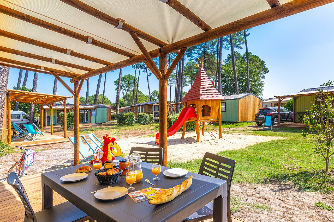 Petit-d�jeuner sur terrasse de Mobil-home avec aire de jeux enfants au camping CAPFUN Pomme de Pin � Saubion (40).