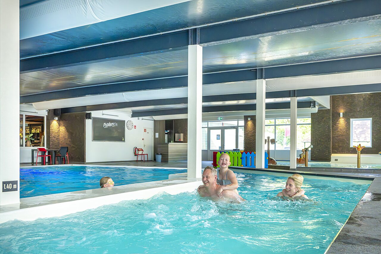Famille joyeuse profitant de la piscine int�rieure chauff�e au camping CAPFUN Ponderosa � Ulicoten.