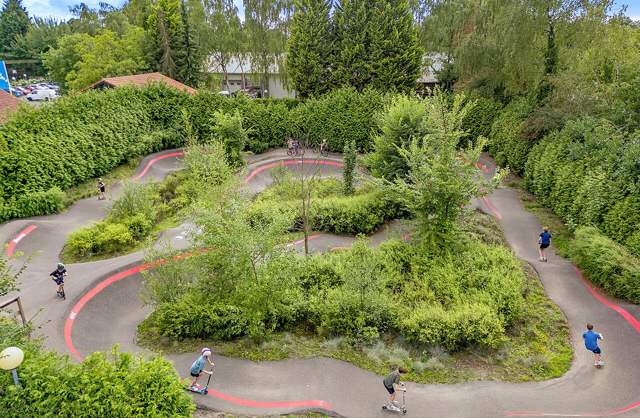 Piste de pumptrack avec enfants en trottinette et v�lo au camping CAPFUN Ponderosa � Ulicoten.