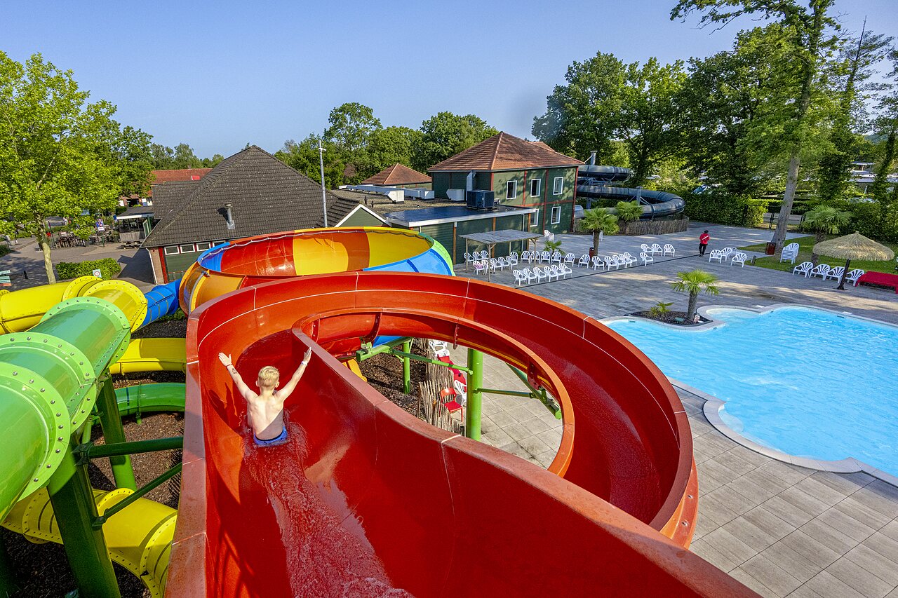 Enfant sur toboggan aquatique g�ant et piscine ext�rieure au camping CAPFUN Ponderosa � Ulicoten.