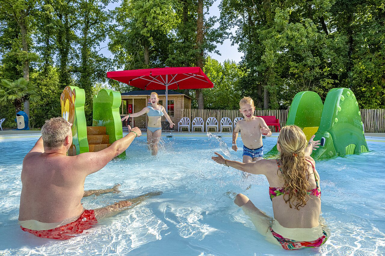 Famille s'amusant dans la piscine avec toboggans aquatiques au camping CAPFUN Ponderosa � Ulicoten