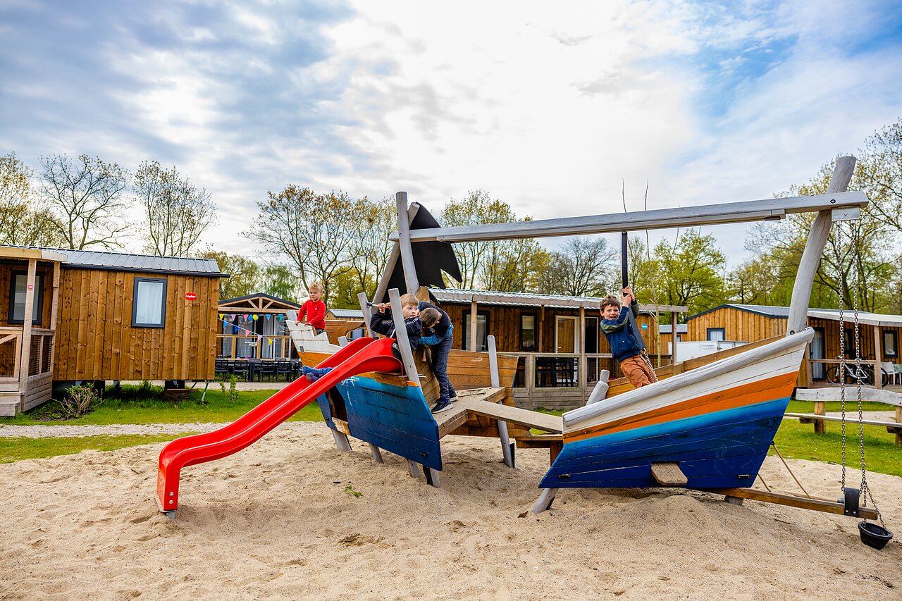 Enfants jouant sur une structure de jeu bateau avec toboggan au camping CAPFUN Ponderosa � Ulicoten.