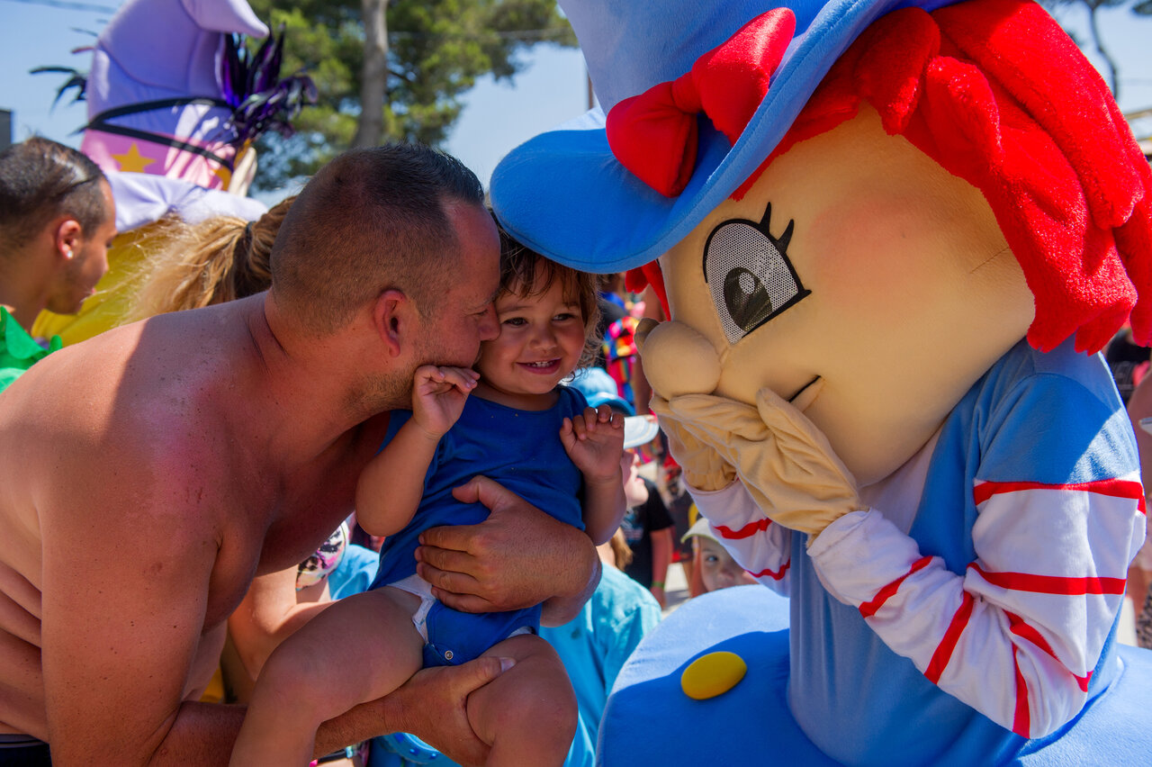 Enfant souriant avec un parent et une mascotte au camping CAPFUN Les Portes du Beaujolais � Anse (69).