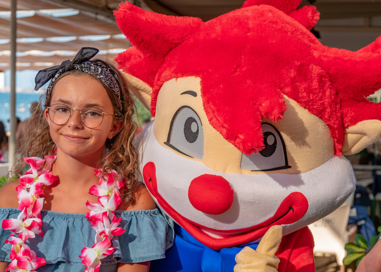 Jeune fille souriante avec collier de fleurs et mascotte au camping CAPFUN Serra de Prades � Vilanova de Prades (43).