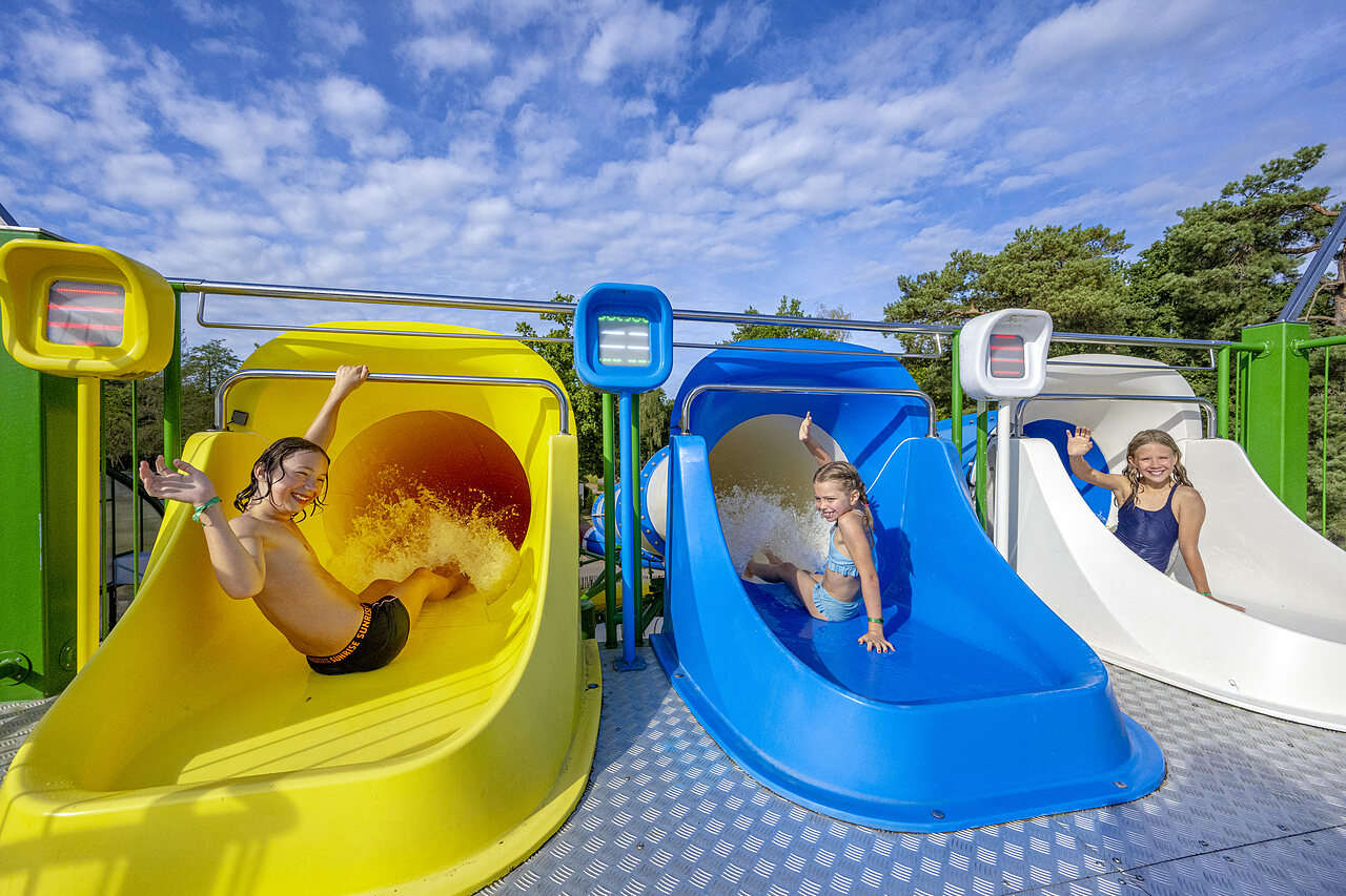Enfants s'amusant sur les toboggans aquatiques color�s au camping CAPFUN Rakelbos � Westelbeers.