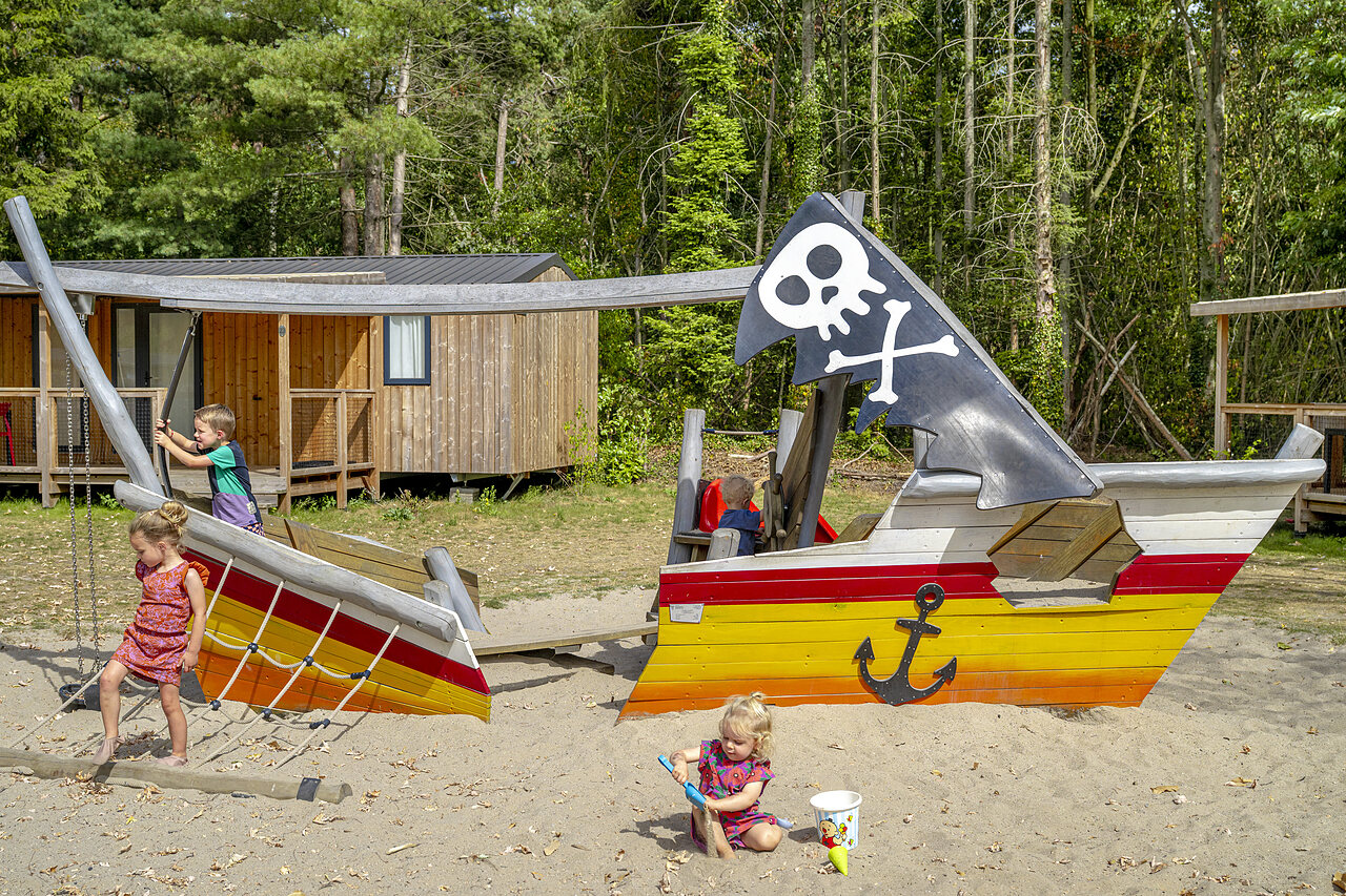 Enfants jouant sur l'aire de jeux bateau pirate avec Mobil-homes au camping CAPFUN Rakelbos � Westelbeers.